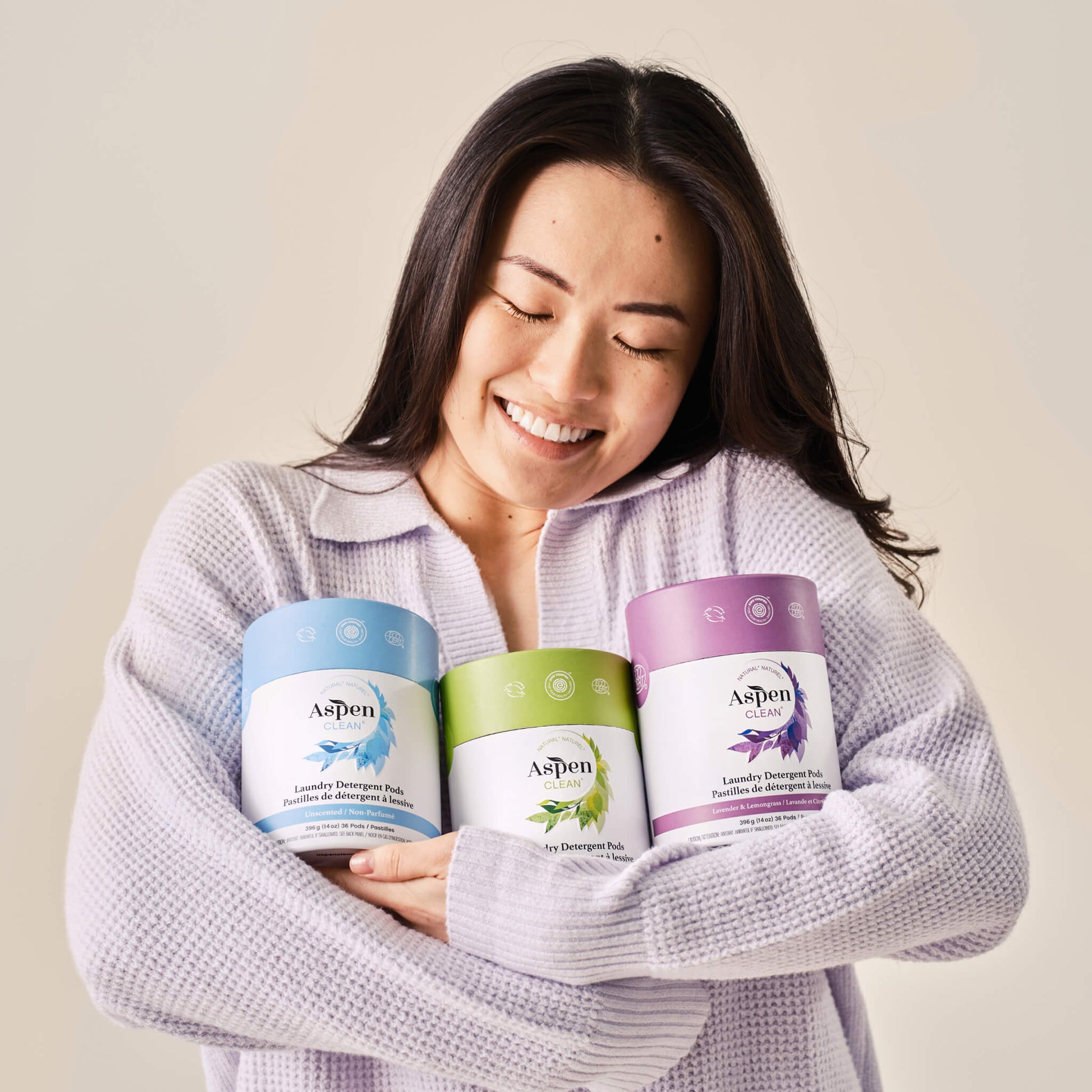 A woman holds AspenClean Laundry Pods 3-pack products