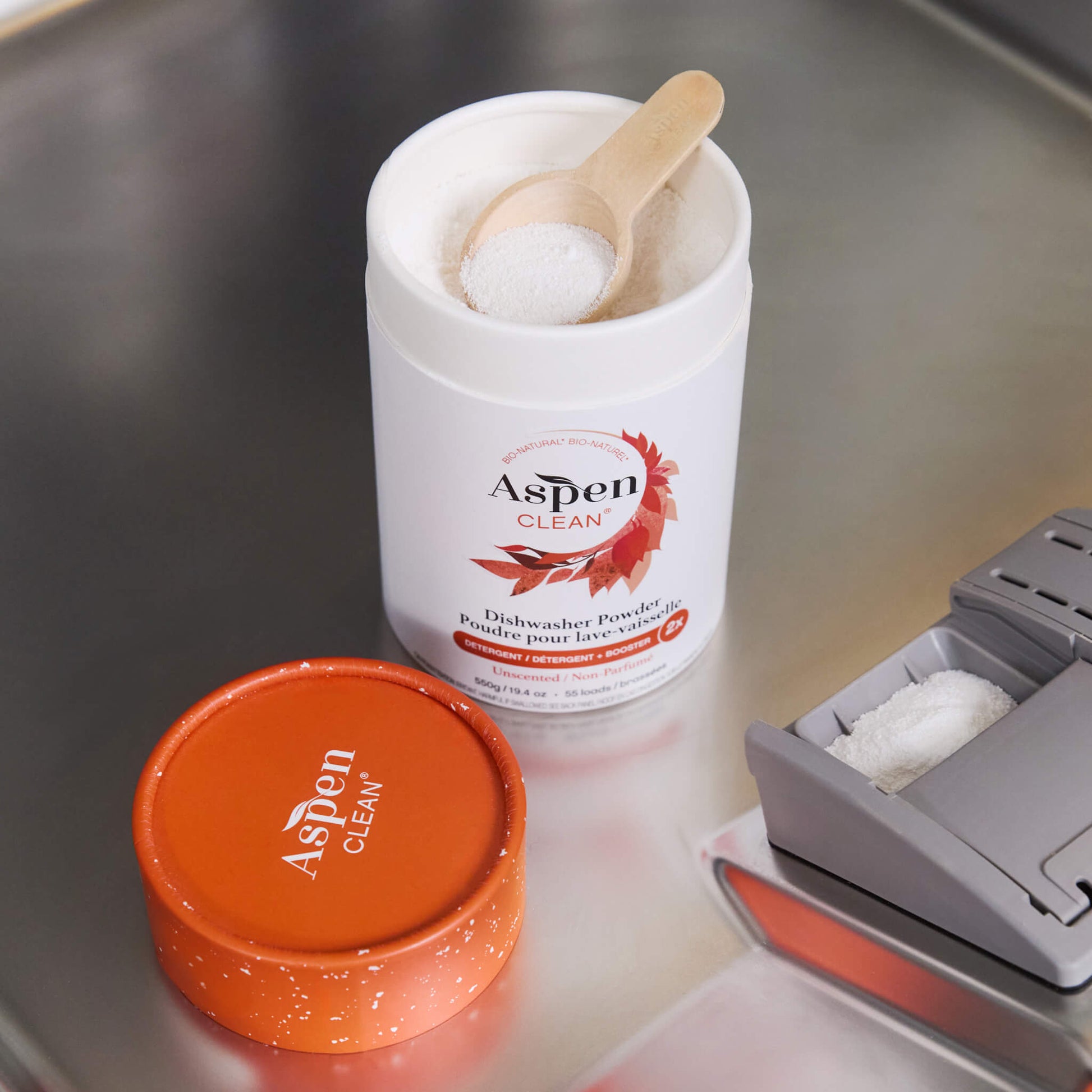 AspenClean dishwasher powder container with a wooden scoop.